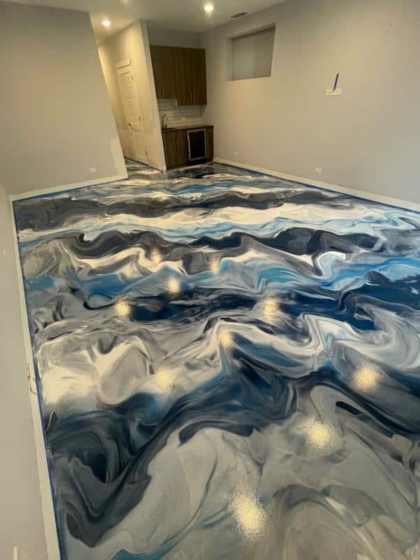 The room features a stunning, glossy, marbled floor in shades of blue and white, with a kitchenette in the background and neutral-colored walls.