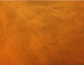 An abstract, textured orange surface, void of people, landmarks, or historical buildings, capturing a warm and earthy atmosphere.