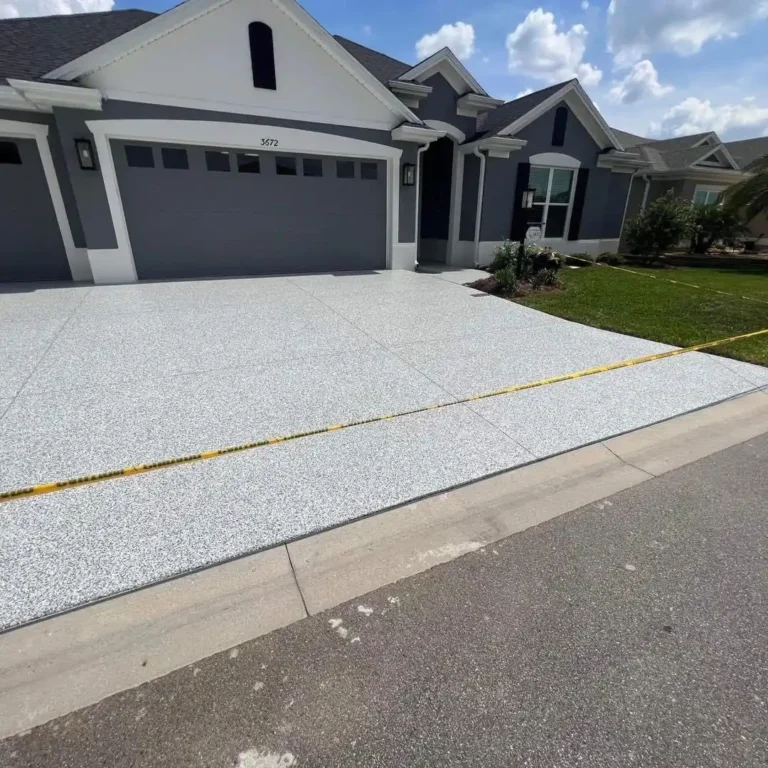 A modern house with a two-car garage, gray exterior, and new concrete driveway on a sunny day. No landmarks or historical buildings visible.