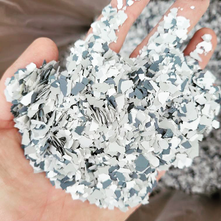 A person holds a handful of gray and white shattered egg shells, creating a textured, mosaic-like appearance in their palm.